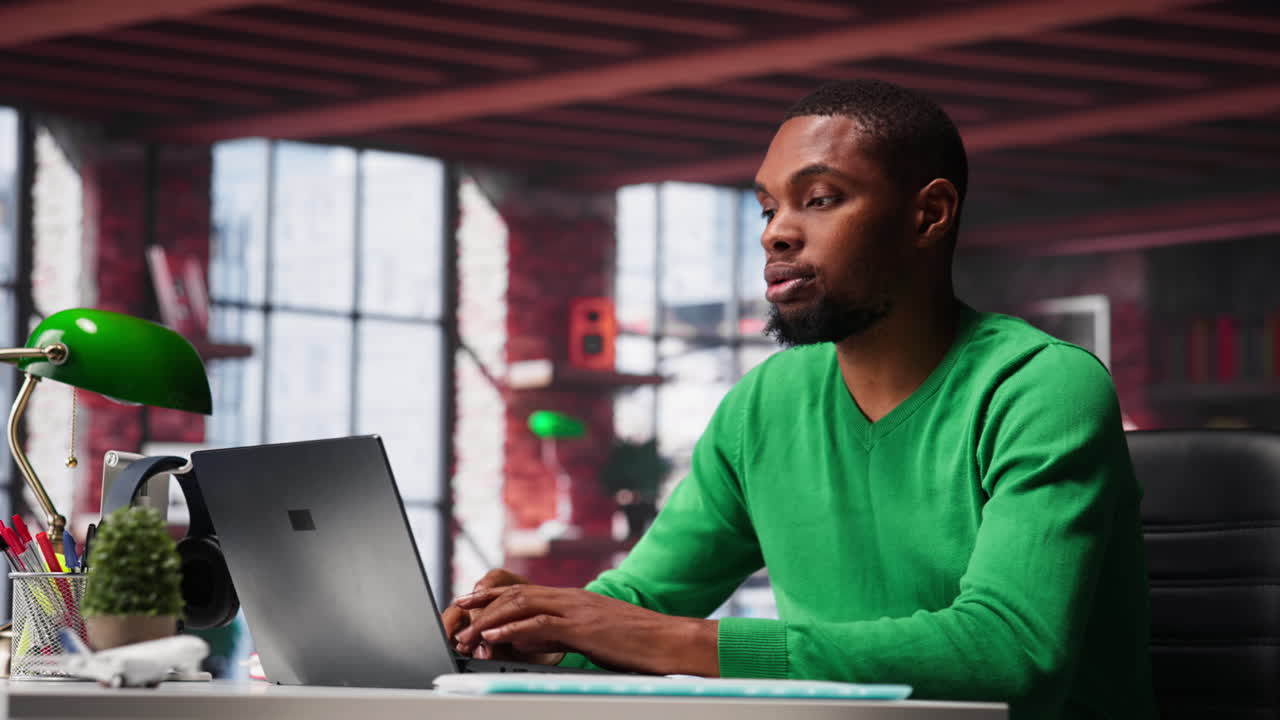 Vertical Video Focused male freelancer browsing web on laptop in a modern studio loft