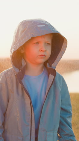 boy gaze remains fixed on horizon despite rain. small child finds solace in rhythmic sound of water in darkest moment of life. face of despair at sunset