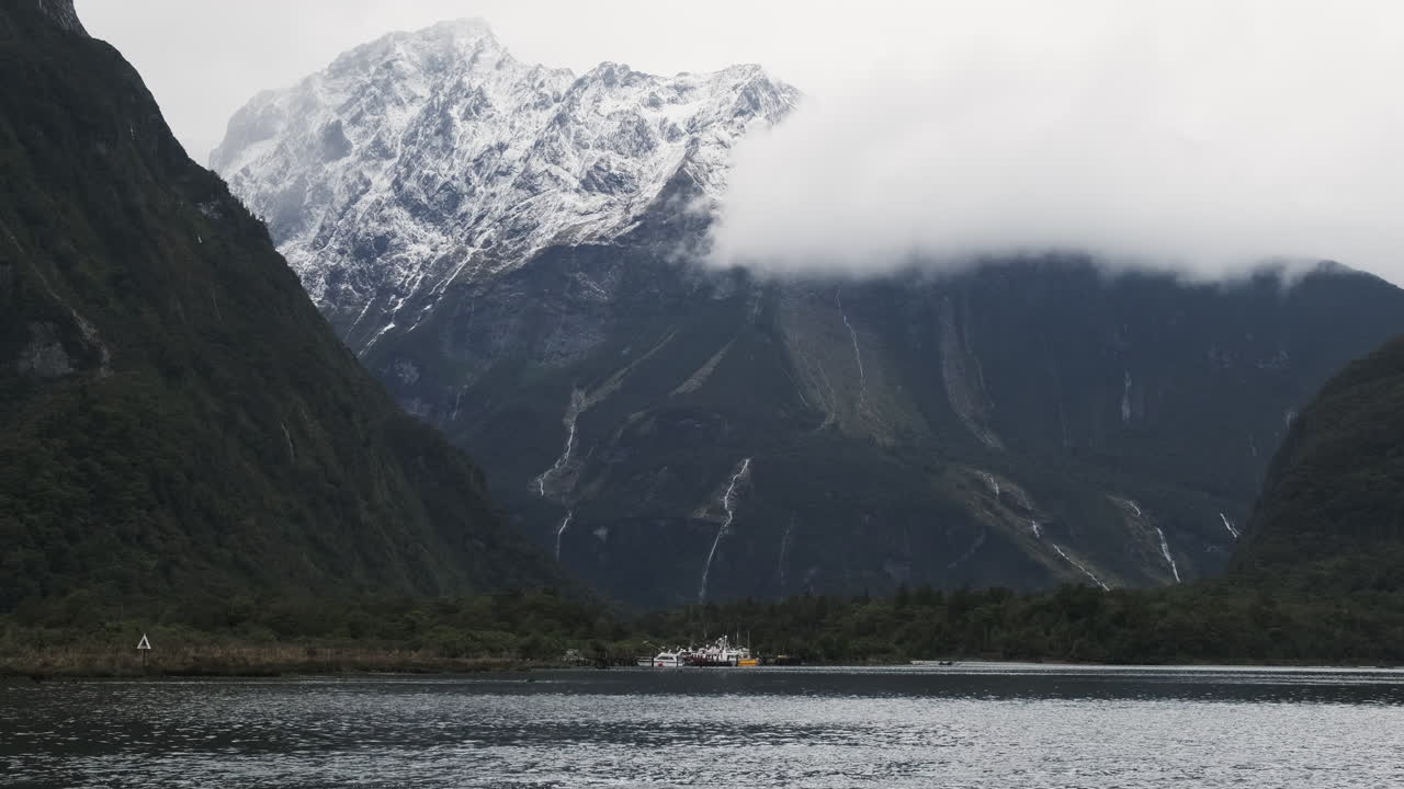 밀포드 사운드, 뉴질랜드 의 거대한 눈 으로  ⁇ 인 절벽 앞 에 정박 한 배 들