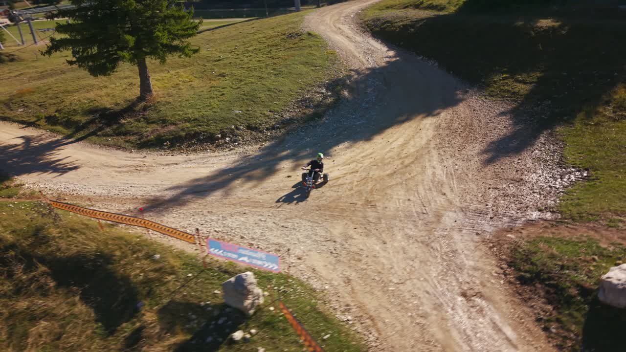 Aerial View Of Tricycle Rider On Dirt Road In Auvergne-Rhône-Alpes France With Green Helmet And Rural Landscape Showing Outdoor Activity And Recreational Transport