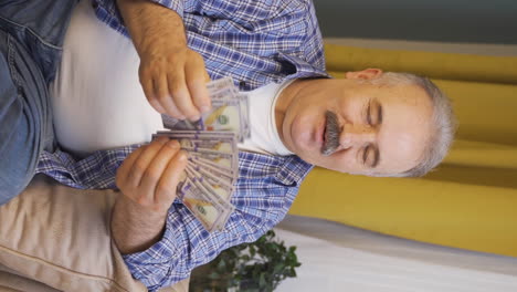 video vertical de un anciano contando dinero mirando a la cámara.