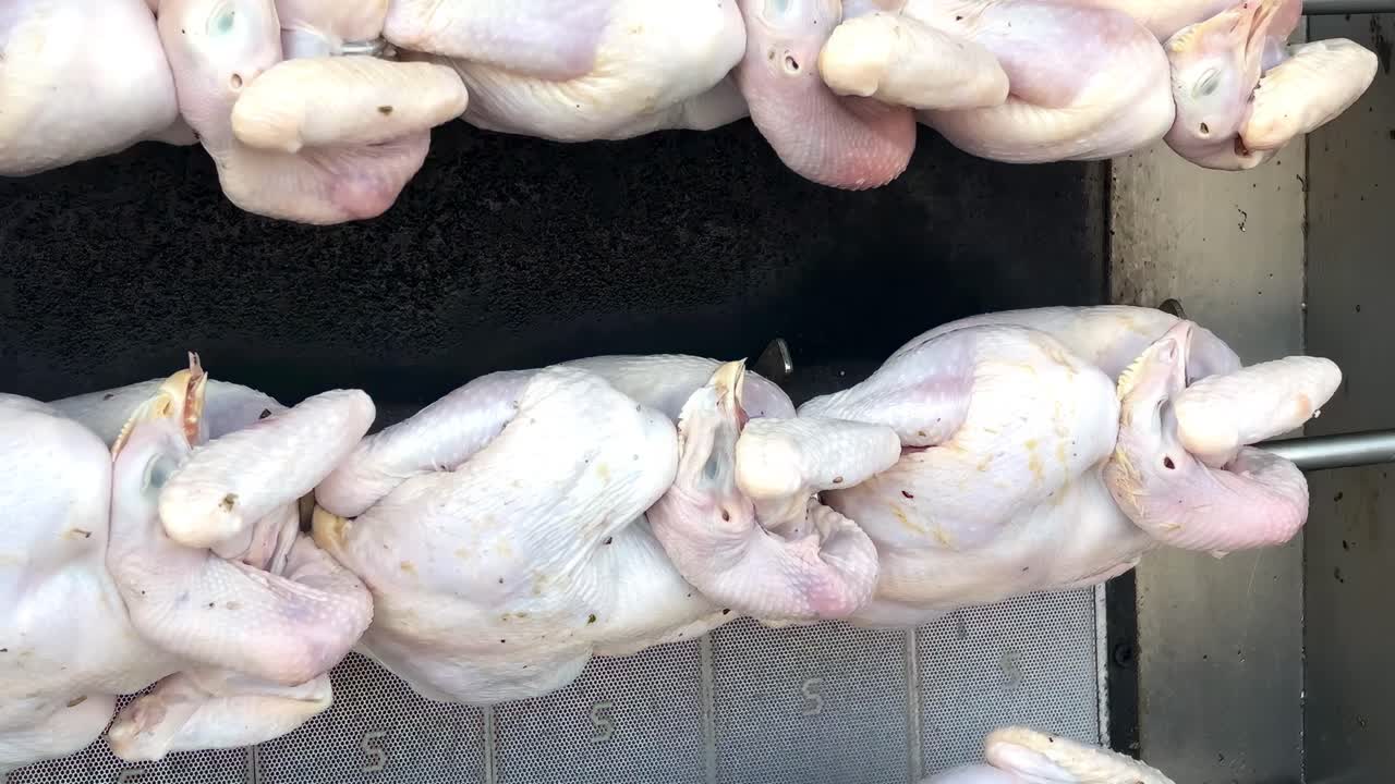 Close-up view of uncooked chickens placed on skewers, ready for grilling.