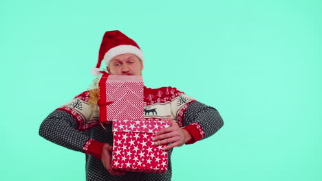 man in christmas red sweater, santa hat, smiling, holding many gift boxes new year presents shopping