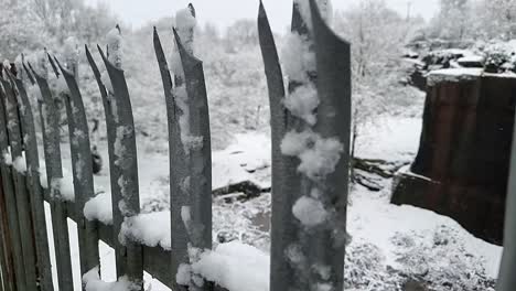 Looking-down-at-wintertime-woodland-forest-quarry-protected-by-snow-covered-metal-security-fence