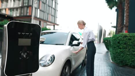 Progressive-businesswoman-plugs-charger-plug-from-charging-station-to-his-EV.