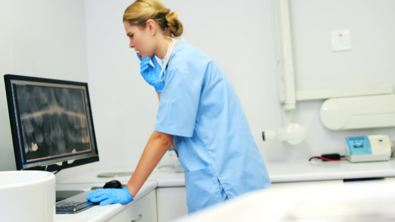 Female nurse examining x-ray report on computer