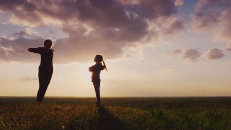 silhouette of a young woman with a child doing fitness in nature 2