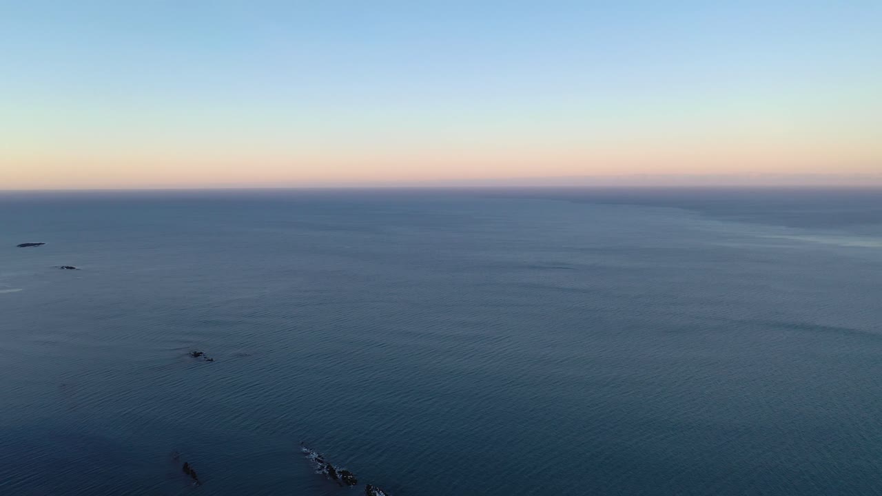 황혼에 바다에서 눈 덮인 평지와 산으로 아름다운 공중 패닝 샷