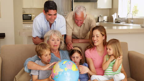 extended family looking at globe together on couch