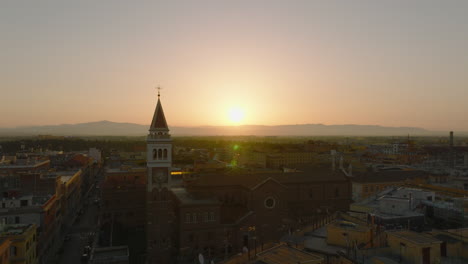 Aerial-view-of-church-and-square-tower-against-sunrise-sky.-Backwards-reveal-of-buildings-in-city-centre.-Rome,-Italy