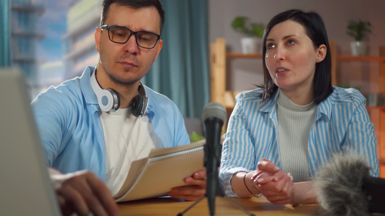 man with glasses and a woman sitting in a home recording studio recording a podcast interview,close up