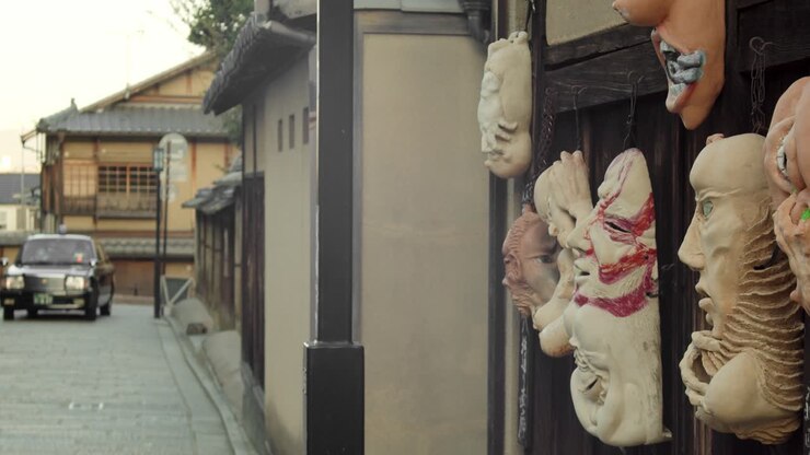 Prise de vue en travelling de masques sur un mur et d'un taxi tournant au coin de la rue à Kyoto, Japon, en ralenti 4K.