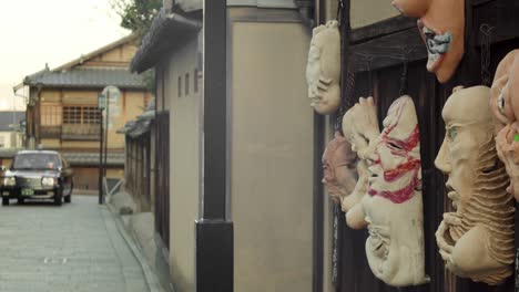 slide shot of masks on the wall and a taxi turning around the corner in kyoto, japan 4k slow motion