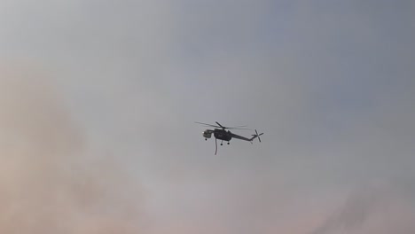 helicóptero de grúa aérea volando sobre bosques y colinas, arrojando agua sobre la naturaleza en llamas