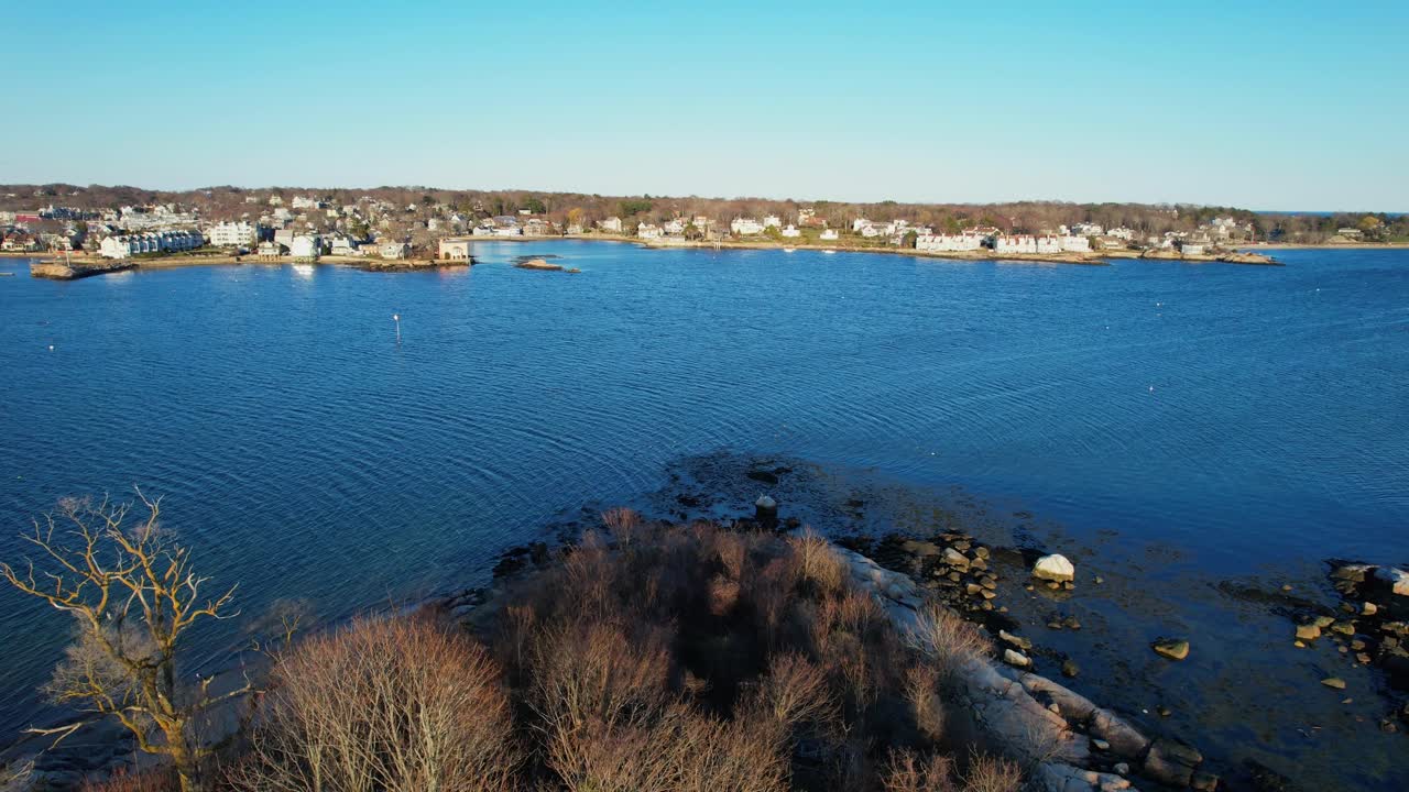 Farol de Annisquam Harbor em uma pequena ilha com a cidade ao fundo em Gloucester, Massachusetts. Aérea frontal, espaço para texto.
