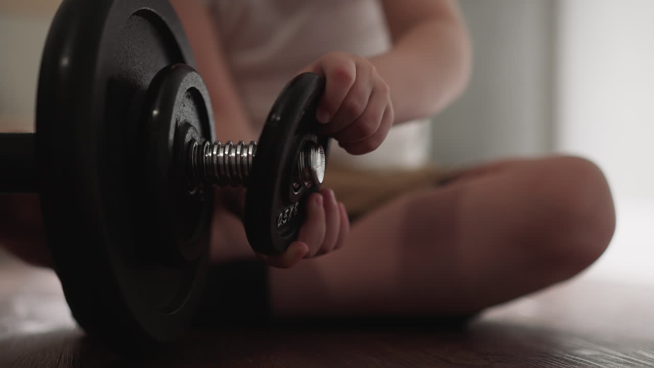 Curious toddler removes gear detail from heavy barbell