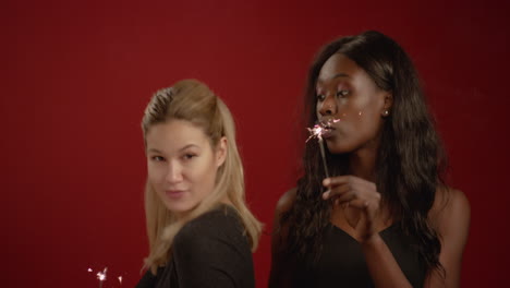 two women dance with sparklers