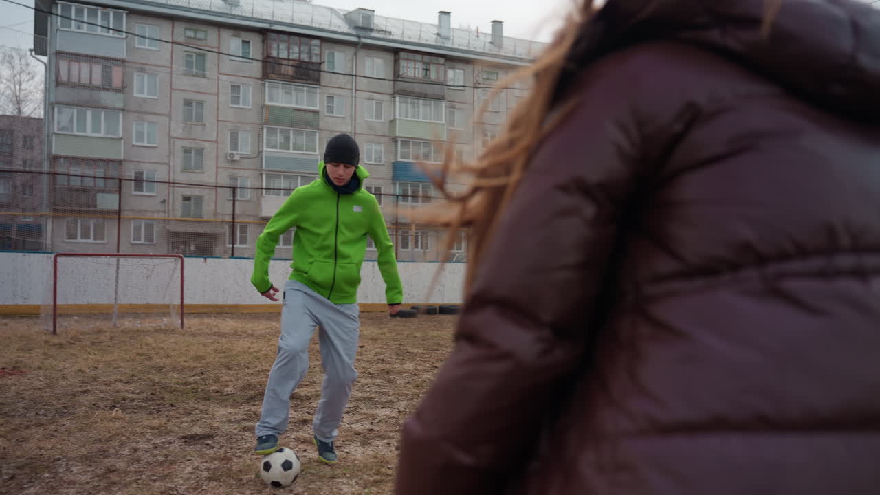 Kvinne utspiller mann under kamp, energisk kvinnelig utøver utfordrer mannlig motstander i livlig kamp, dynamisk scene av kvinne som snapper ballen fra mannen under en spennende sportsduell utendørs