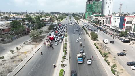 Aerial-drone-backward-moving-shot-over-heavy-traffic-movement-on-a-main-road-in-Karachi-city,-Pakistan-on-a-sunny-day