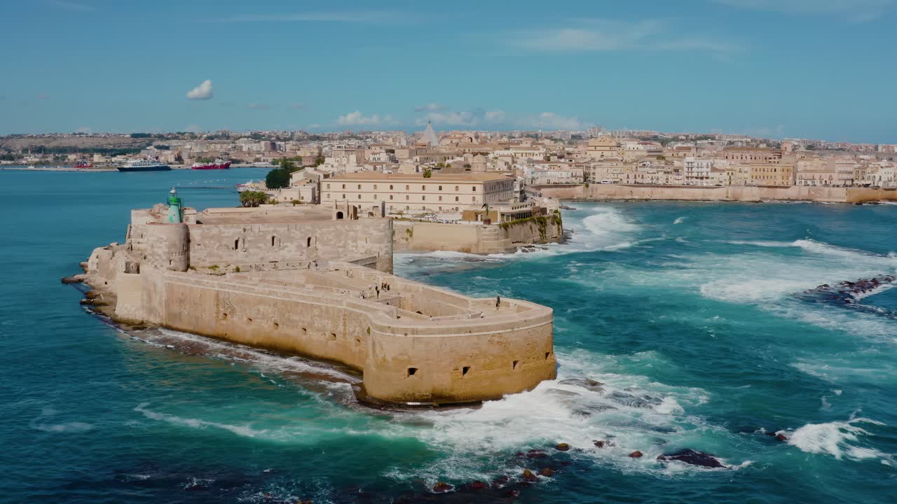 Aerial view of Medieval castle in Ortigia island, Sicily. Big waves crashing into the fortress walls. Drone shot of Castello Maniace surrounded by Mediterranean sea in Ortigia island, Syracuse.