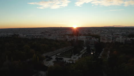 Vuelo-Nocturno-Sobre-El-Parque-Del-Retiro.-Vista-Elevada-Del-Jardín-Del-Parterre-Decorativo-Y-La-Ciudad-Contra-La-Puesta-De-Sol.