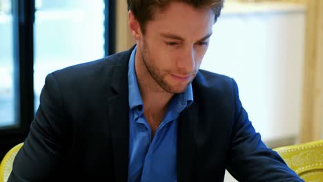man using digital tablet while eating pastry