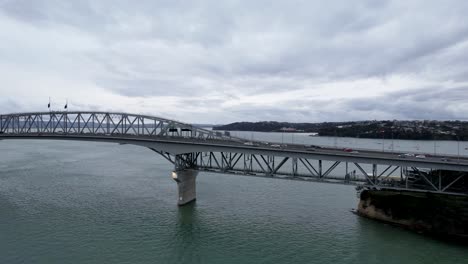 A-4k-aerial-perspective-captures-the-Auckland-Harbour-Bridge-within-the-picturesque-landscape-of-Auckland,-New-Zealand-with-car-traffic