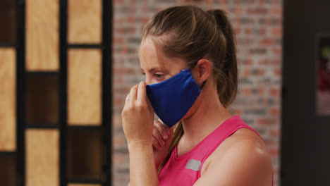 portrait of caucasian woman at a sports centre adjusting her face mask