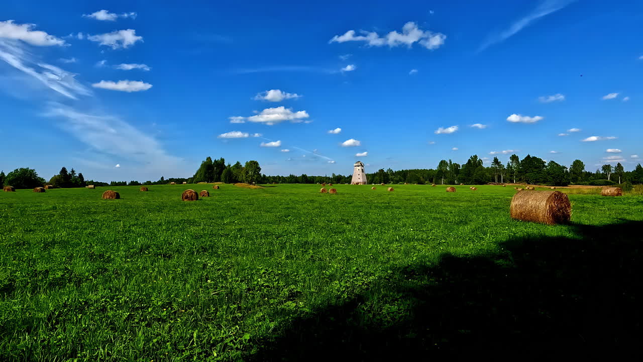 antiguo molino y prado verde con rollos de heno, vista de movimiento
