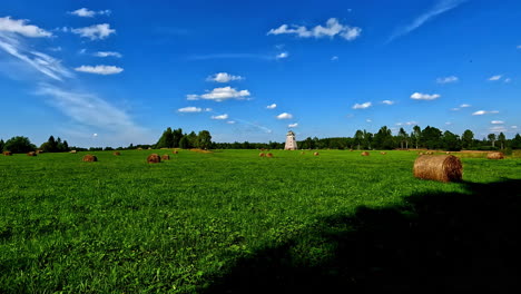 Ancient-mill-and-green-meadow-with-hay-rolls,-motion-view