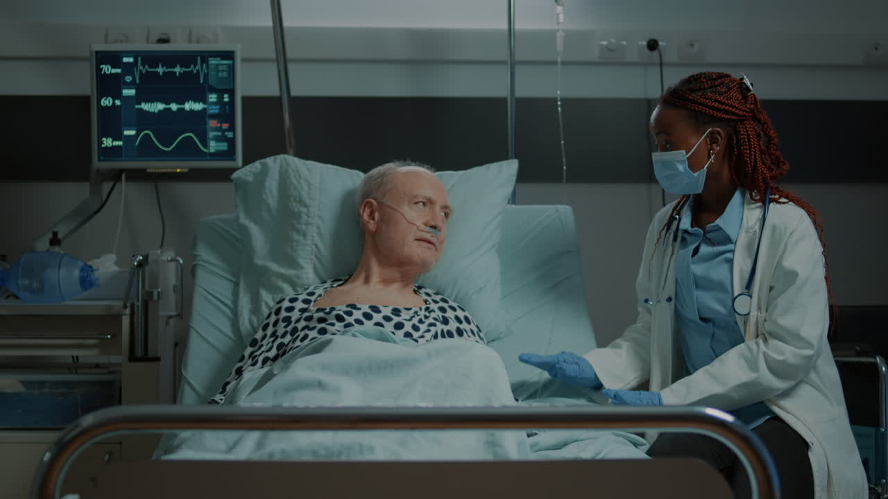 African american doctor talking to sick patient in hospital ward