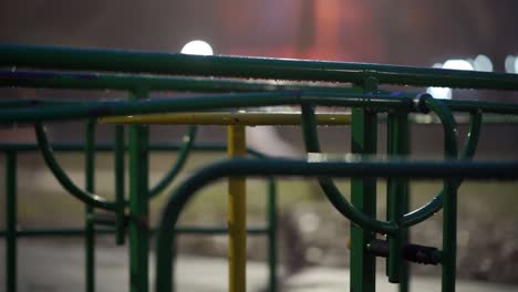 wet carousel spinning at empty children's playground in city park on an autumn night.