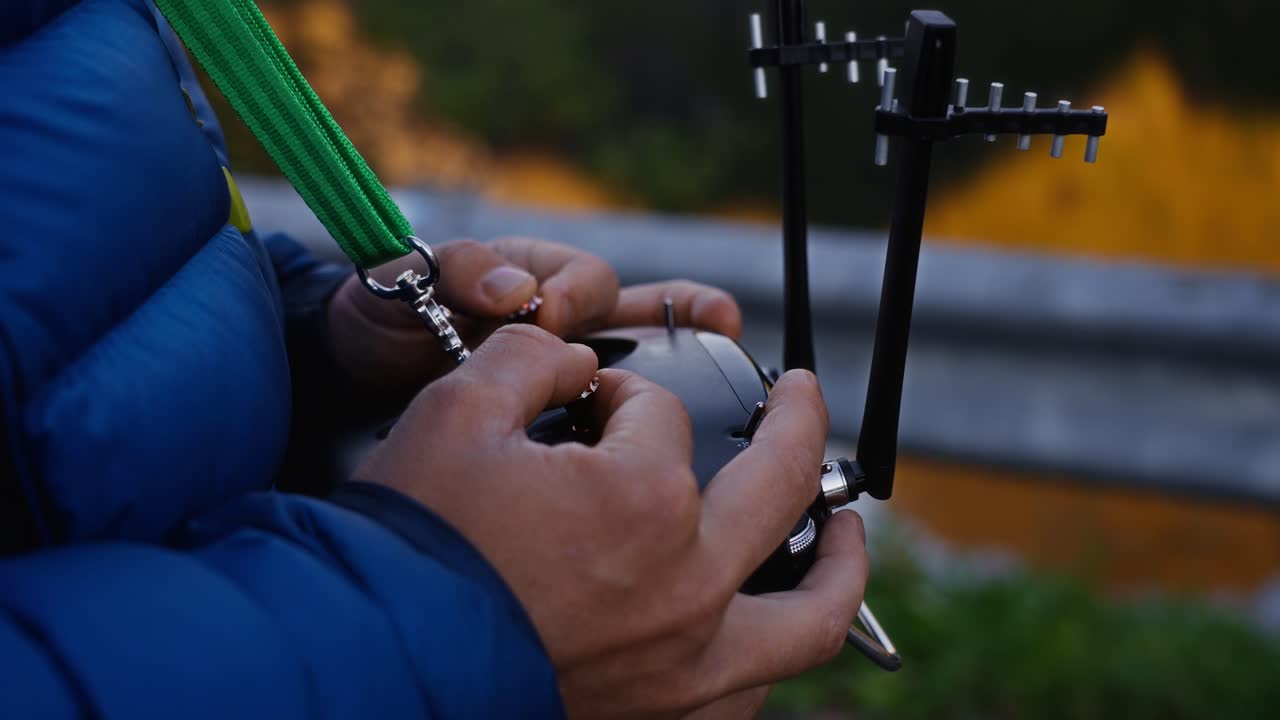 A person operating a drone controller outdoors with focus on hands and antennas