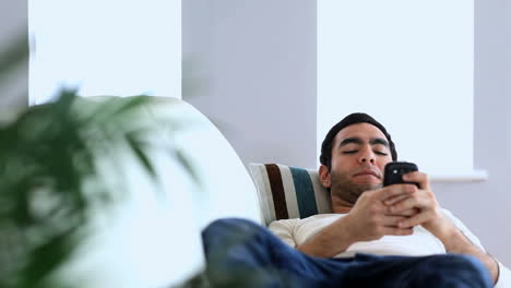 man using his smartphone laid on a couch