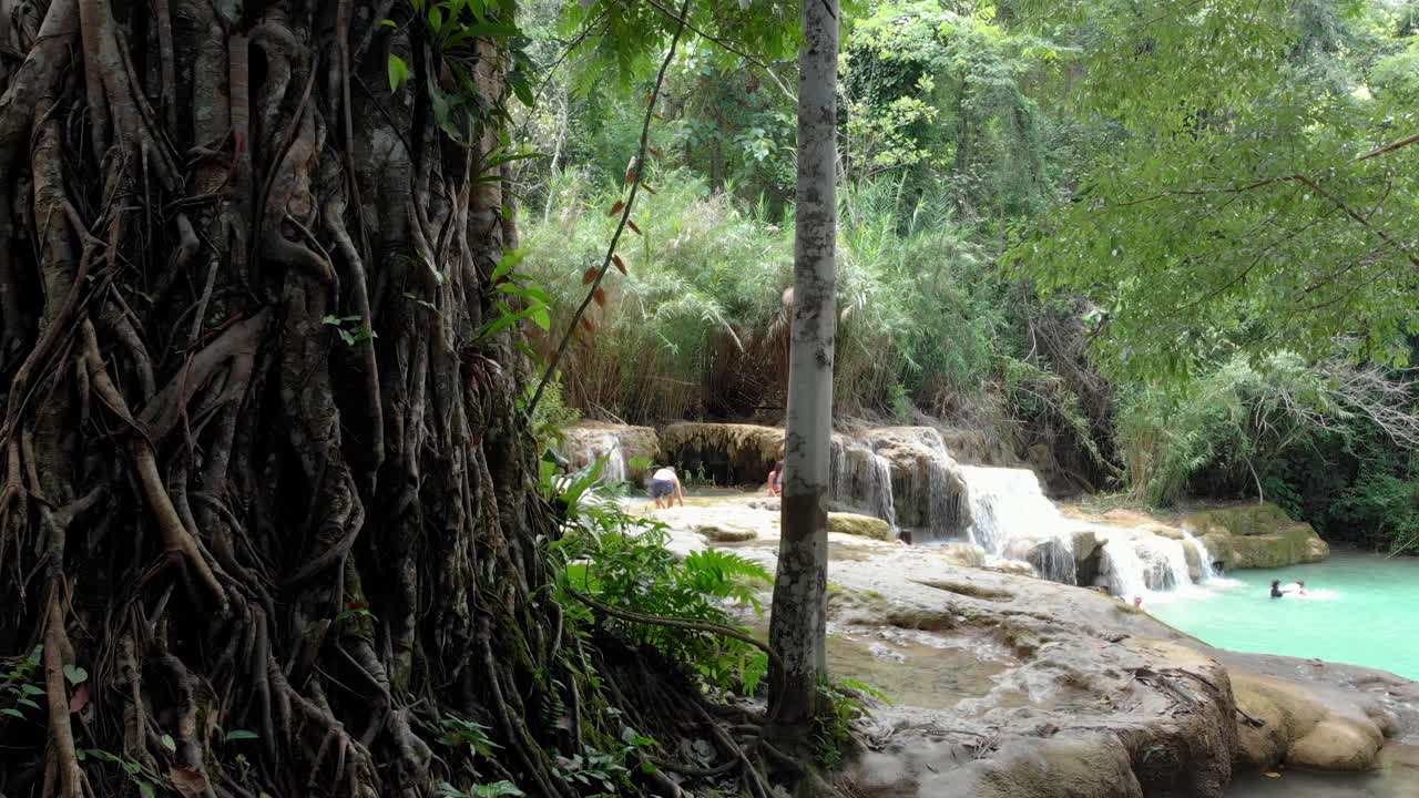 Ripresa in 4K di turisti che si divertono a sguazzare nelle acque del primo livello della famosa cascata Kuang Si in Laos, Sud-est asiatico