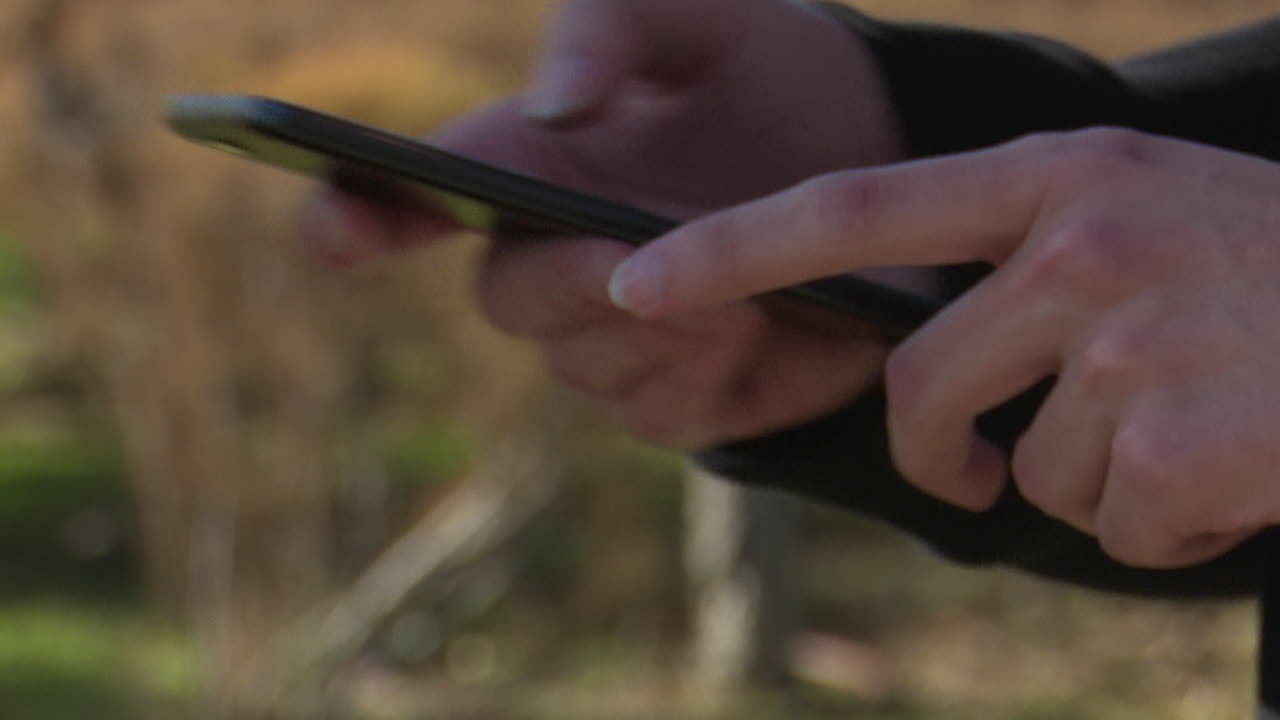 야외에서 스마트폰을 사용하는 사람