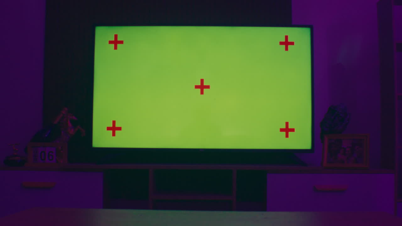 TV screen with green screen and tracking markers in a cozy dimly lit room