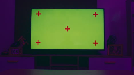 tv screen with green screen and tracking markers in a cozy dimly lit room