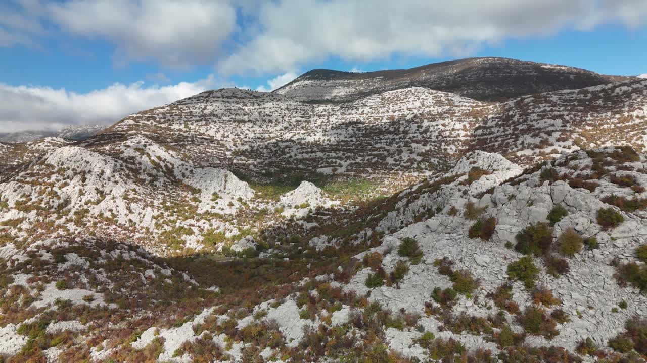 A close‑up drone flight over Velebit’s autumn peaks reveals orange mountain hues, winding paths, and the distant Adriatic Sea, showcasing Croatia’s rugged beauty in a sweeping aerial panorama