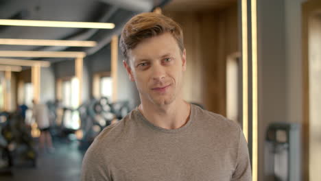 confident bodybuilder smiling at gym. sportsman standing in fitness club