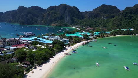 Turquoise-water-laps-gently-at-the-shore-of-a-tropical-island,-with-boats-dotting-the-seascape-and-lush-green-hills