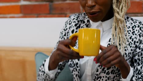 Female-executive-drinking-coffee-while-working-on-digital-tablet