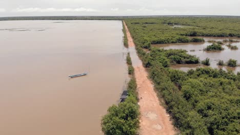 Volando-Sobre-Un-Camino-De-Tierra-Entre-El-área-Inundada-Y-El-área-De-árboles-En-El-Campo