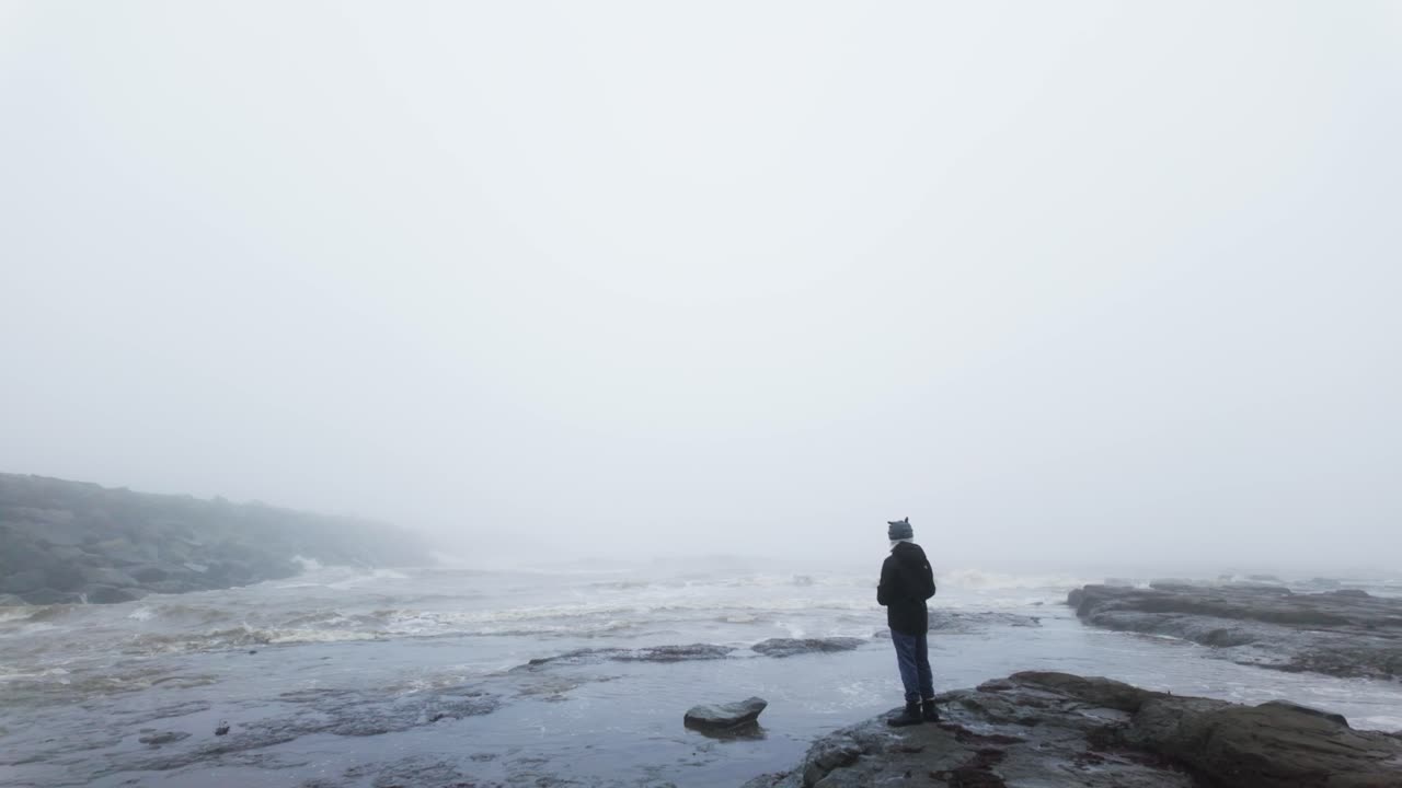 niño de pie en las rocas en un paisaje costero