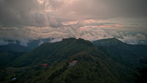 Wolken-Ziehen-Schnell-über-Einen-Grünen-Hügel,-Dichte-Vegetation,-Windkraftanlage-In-Costa-Rica