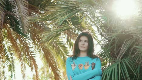 woman in a teal sweater under palm trees