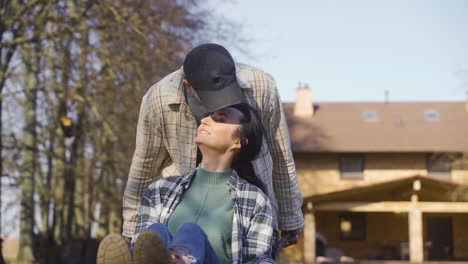 Front-view-of-caucasian-man-carrying-his-partner-on-a-wheelbarrow-in-the-countryside.-The-woman-pets-her-dog