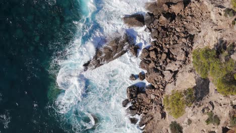 Top-Down-Over-Waves-Crashing-On-The-Rocks,-Cliffs-Of-Majorca,-Spain,-Europe