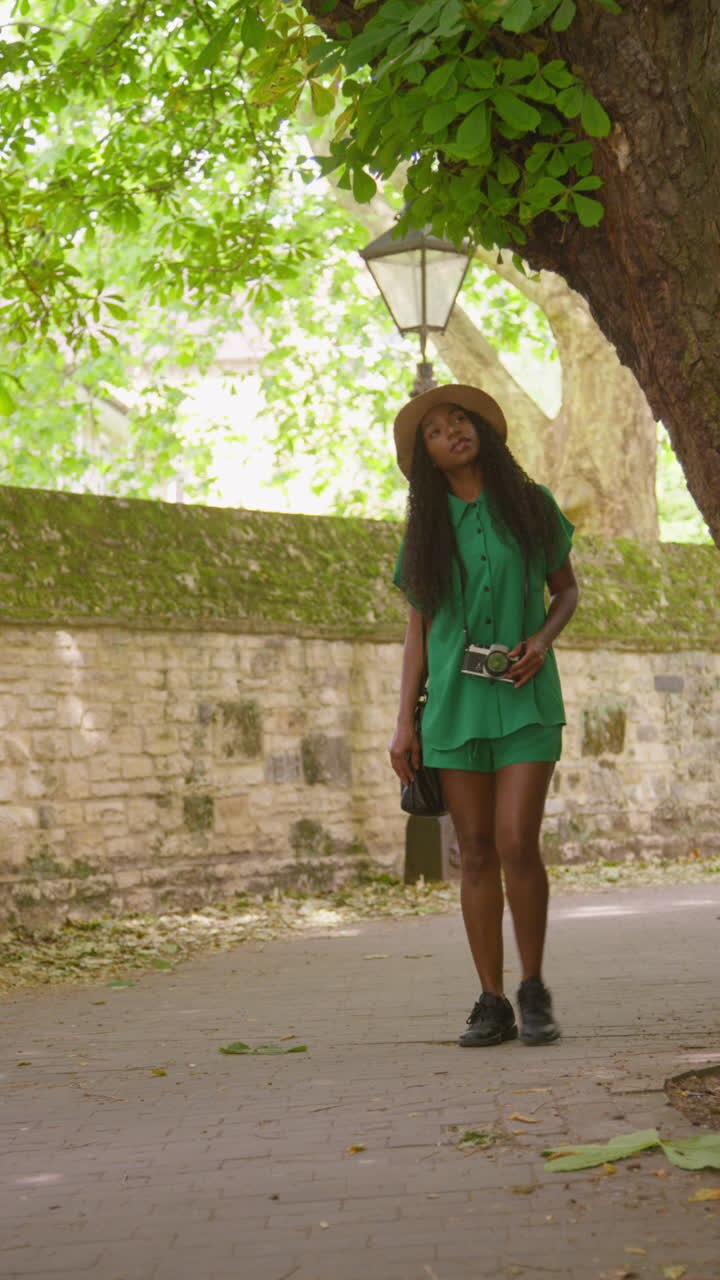 Vertical Video Of Female Tourist With Camera On Vacation In Oxford UK Exploring City Street Walking Along Lamb And Flag Passage Touching Tree 4 Shot In Real Time