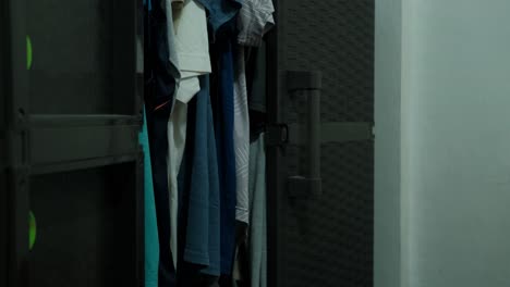 medium shot of male person opening plastic wardrobe and hanging shirt inside.